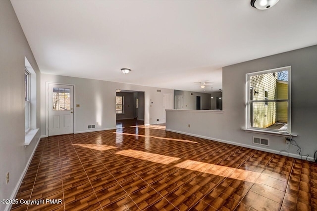 unfurnished living room featuring baseboards, visible vents, and wood finished floors