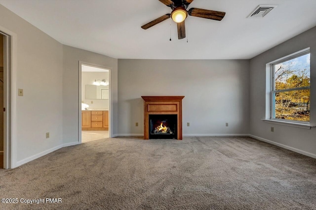 unfurnished living room with a warm lit fireplace, visible vents, light carpet, and baseboards