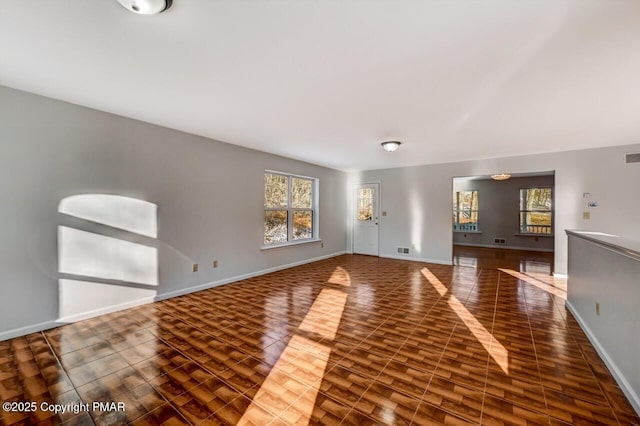 unfurnished living room with wood finished floors, visible vents, and baseboards