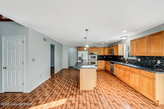 kitchen featuring tasteful backsplash, baseboards, visible vents, stainless steel appliances, and a sink