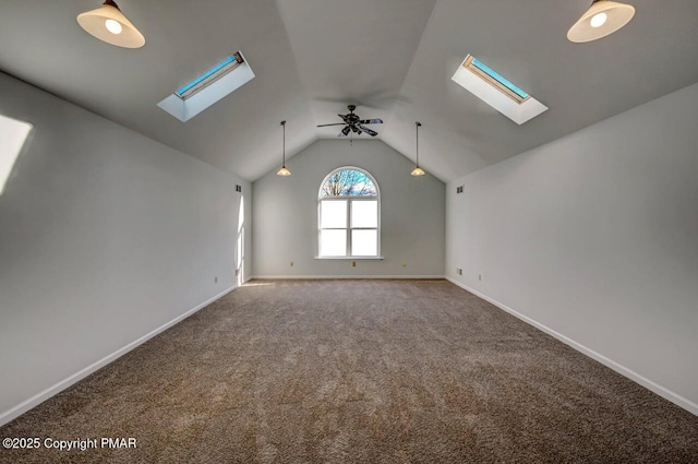 interior space featuring lofted ceiling with skylight, a ceiling fan, and baseboards