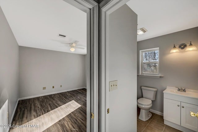 bathroom with baseboards, visible vents, a ceiling fan, toilet, and vanity