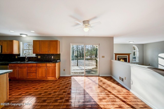 kitchen featuring a sink, visible vents, brown cabinetry, and decorative backsplash