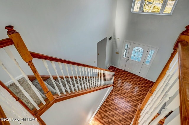 foyer entrance featuring a towering ceiling, stairway, a wealth of natural light, and wood finished floors