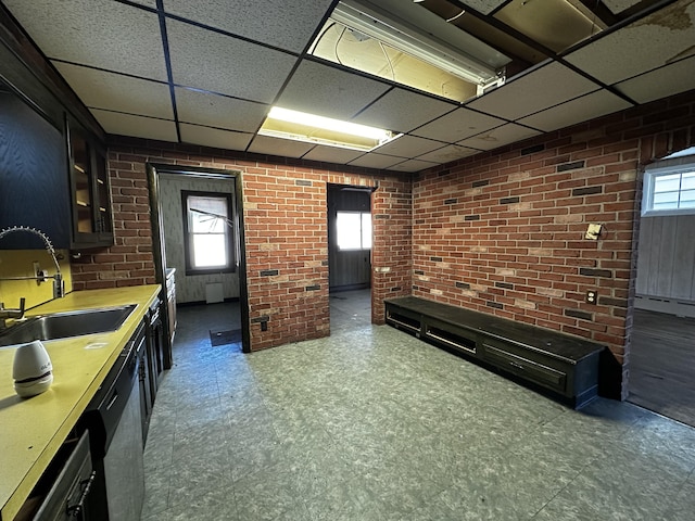 interior space featuring tile patterned floors, brick wall, a paneled ceiling, and a sink