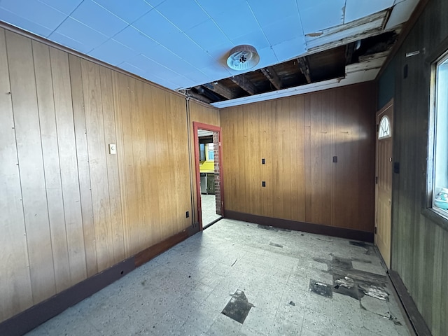 unfurnished room with tile patterned floors, baseboards, and wood walls