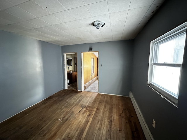 unfurnished room with wood finished floors and a baseboard radiator