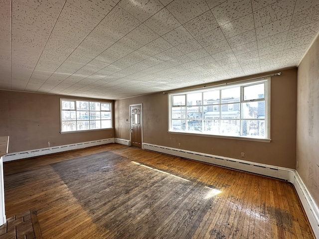 spare room with hardwood / wood-style floors, a healthy amount of sunlight, a baseboard heating unit, and a baseboard radiator