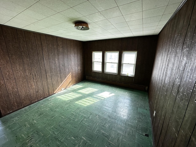 unfurnished room with tile patterned floors, a baseboard radiator, and wood walls