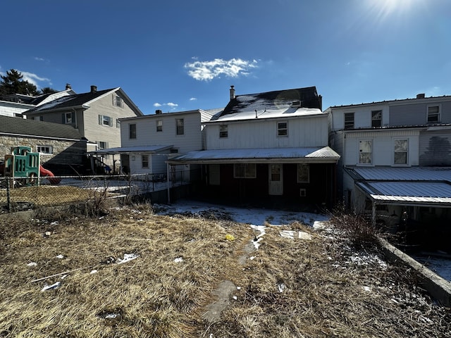 rear view of property with a playground and fence