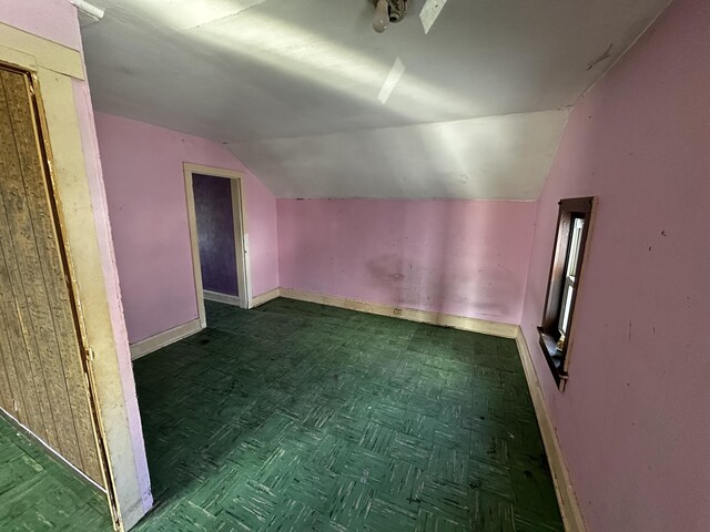 additional living space with baseboards and lofted ceiling