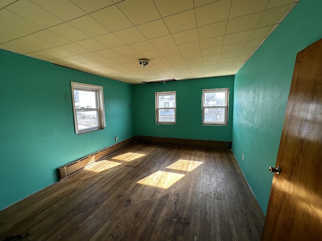 empty room with baseboards, wood-type flooring, and baseboard heating