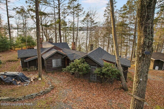 view of side of home with a shingled roof and a chimney