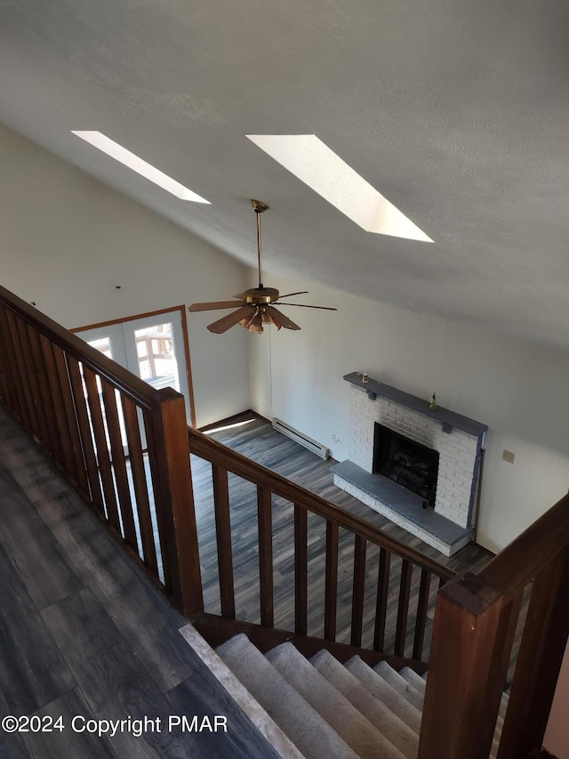 1584 Black Birch Way, Tobyhanna, PA 18466 - stairs featuring a skylight, wood finished floors, a brick fireplace, a ceiling fan, and vaulted ceiling