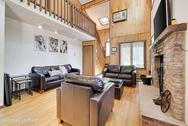 138 Banbury Dr, Bushkill, PA 18324 - living room featuring rail lighting, wood walls, an AC wall unit, light wood-type flooring, and a high ceiling