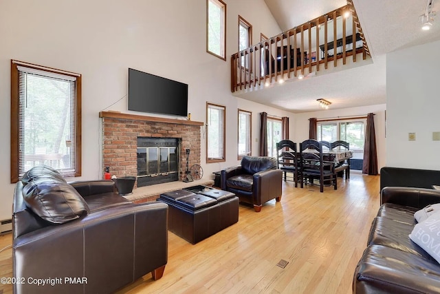 138 Banbury Dr, Bushkill, PA 18324 - living area featuring hardwood / wood-style floors, a fireplace, a baseboard heating unit, and a towering ceiling