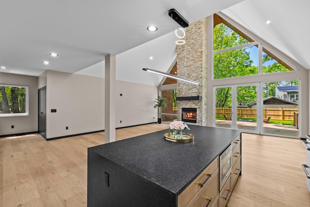 2154 Valleyview Dr, Bushkill, PA 18324 - kitchen featuring open floor plan, stainless steel microwave, light wood finished floors, a stone fireplace, and lofted ceiling