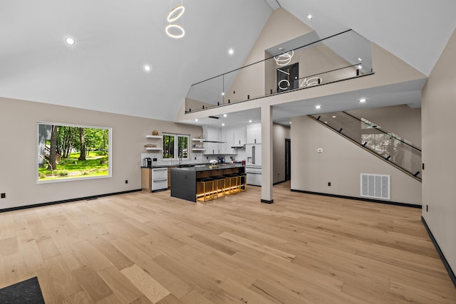 2154 Valleyview Dr, Bushkill, PA 18324 - kitchen featuring open shelves, dishwasher, high vaulted ceiling, light wood-style flooring, and white cabinets