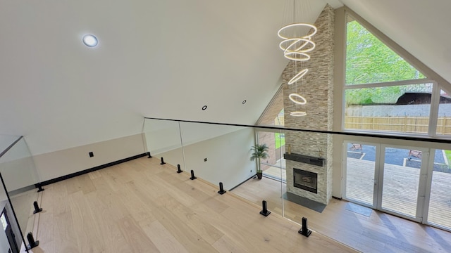 2154 Valleyview Dr, Bushkill, PA 18324 - unfurnished living room with wood finished floors, healthy amount of natural light, high vaulted ceiling, a stone fireplace, and a chandelier