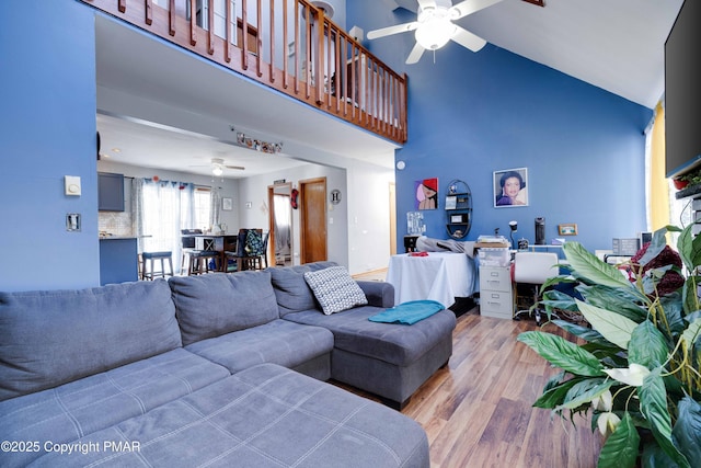 living room featuring a towering ceiling, light hardwood / wood-style floors, and ceiling fan