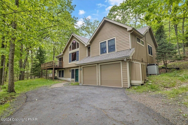 rustic home featuring a shingled roof, an attached garage, board and batten siding, central AC, and driveway