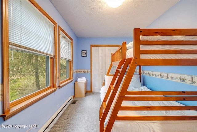 carpeted bedroom with baseboards, visible vents, a textured ceiling, and baseboard heating