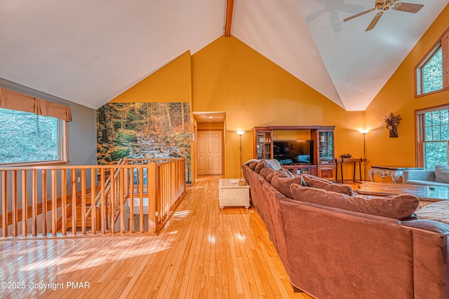 living area with light wood-type flooring, high vaulted ceiling, and a ceiling fan