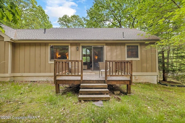 back of property featuring a yard, board and batten siding, a wooden deck, and roof with shingles