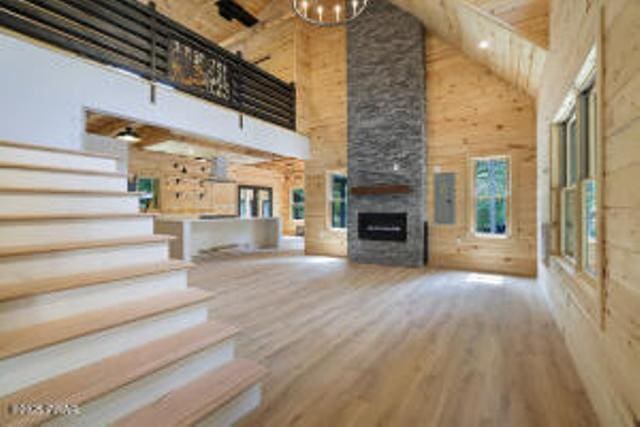 118 Eagle Rock Rd, Lackawaxen, PA 18435 - unfurnished living room featuring high vaulted ceiling, wood finished floors, a fireplace, stairway, and a chandelier
