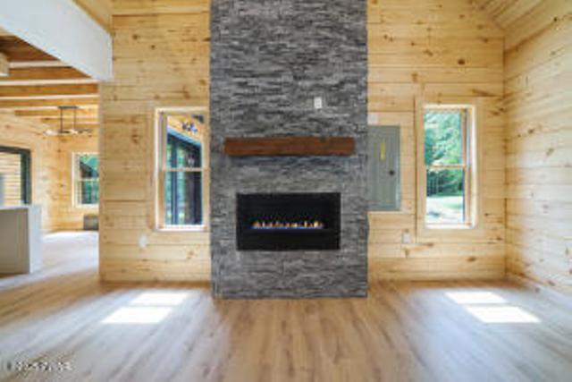 118 Eagle Rock Rd, Lackawaxen, PA 18435 - unfurnished living room featuring wood finished floors, a fireplace, wood walls, and a towering ceiling