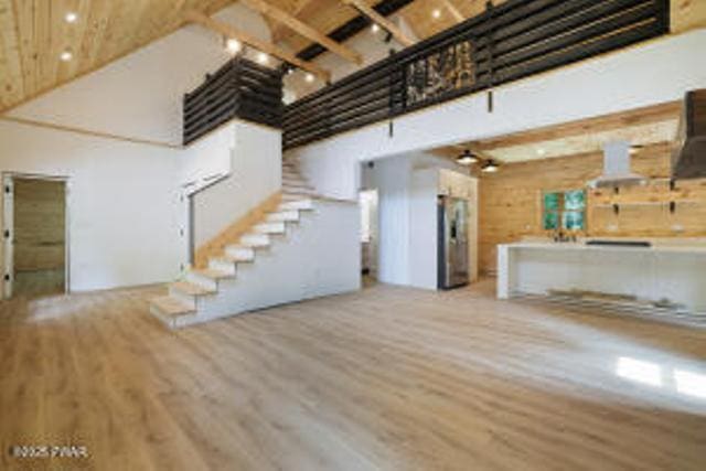118 Eagle Rock Rd, Lackawaxen, PA 18435 - unfurnished living room with wood finished floors, beamed ceiling, a high ceiling, stairway, and track lighting