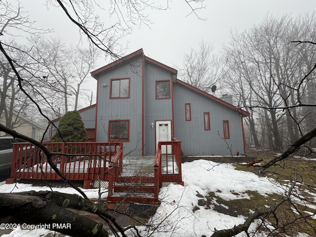 snow covered rear of property featuring a deck