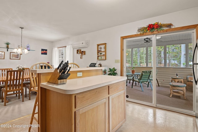 kitchen with a kitchen island, light countertops, hanging light fixtures, a wall mounted AC, and a kitchen bar