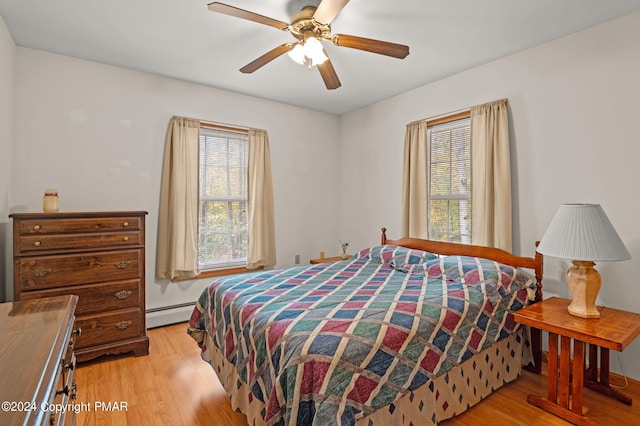 bedroom with light wood-type flooring, baseboard heating, and a ceiling fan