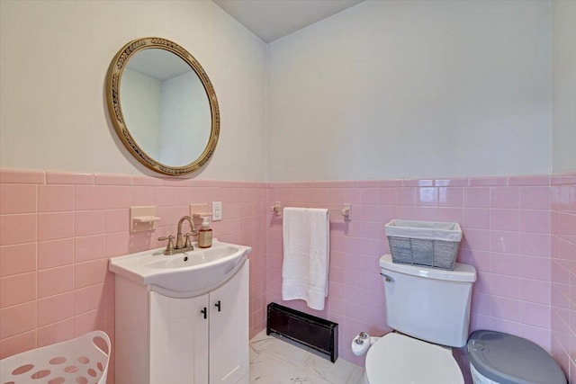 bathroom featuring toilet, marble finish floor, wainscoting, and vanity