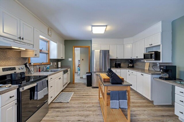 kitchen with appliances with stainless steel finishes, white cabinets, a sink, and under cabinet range hood