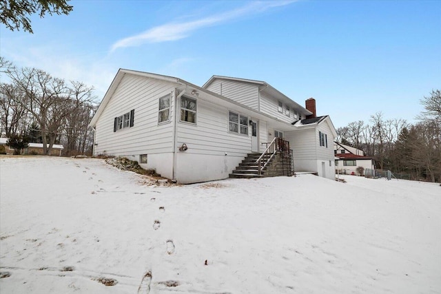 snow covered rear of property with a chimney