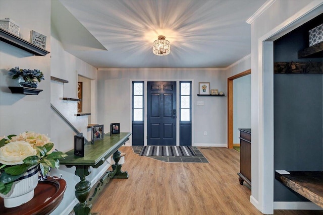 foyer featuring ornamental molding, stairway, wood finished floors, and baseboards