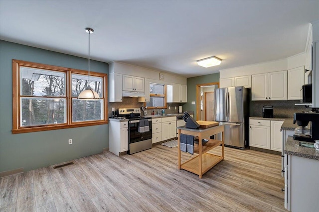 kitchen with light wood finished floors, visible vents, stainless steel appliances, white cabinetry, and backsplash