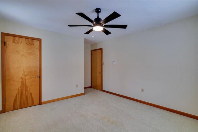 unfurnished bedroom featuring a ceiling fan, light carpet, and baseboards