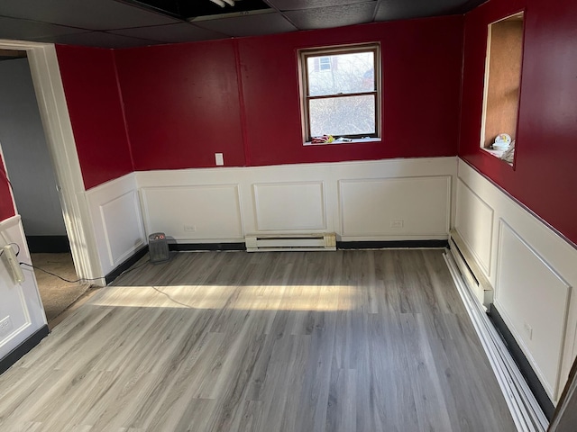 135 Marsh Rd, Stroudsburg, PA 18360 - unfurnished room with a baseboard radiator, a decorative wall, a paneled ceiling, light wood finished floors, and wainscoting