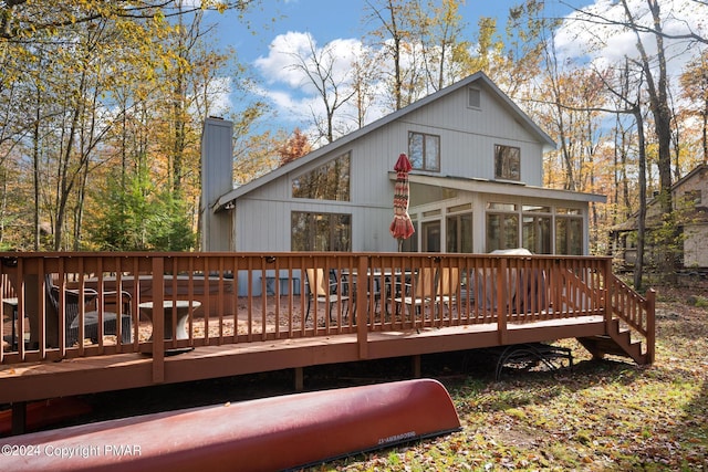 rear view of house with a chimney, a wooden deck, and a sunroom