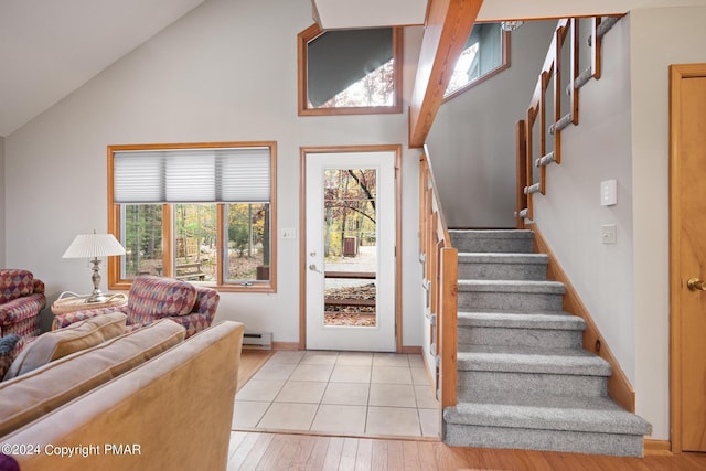 foyer with light wood-type flooring, stairs, vaulted ceiling, and baseboard heating