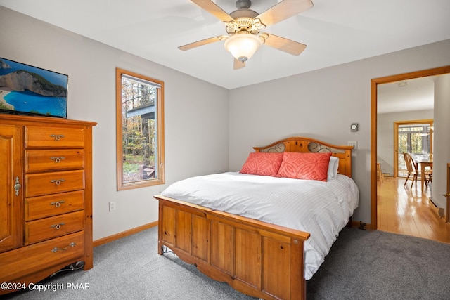 bedroom with a ceiling fan, light carpet, and baseboards