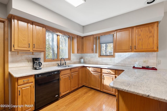 kitchen with light wood-style floors, dishwasher, a sink, and tasteful backsplash