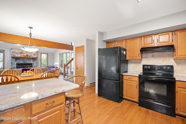 kitchen featuring decorative backsplash, under cabinet range hood, a healthy amount of sunlight, black appliances, and a fireplace