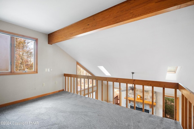 interior space with vaulted ceiling with skylight, carpet floors, and baseboards