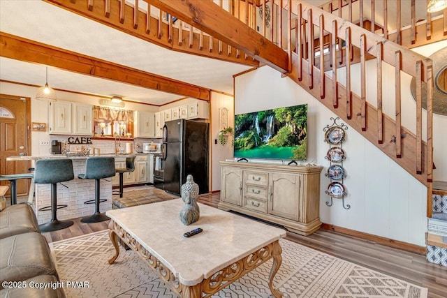 living area featuring light wood-style floors, stairs, and baseboards