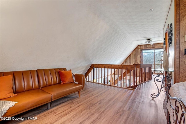 interior space with vaulted ceiling, wood finished floors, a textured ceiling, and ceiling fan