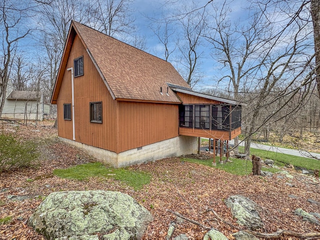 view of side of home featuring a sunroom and a shingled roof